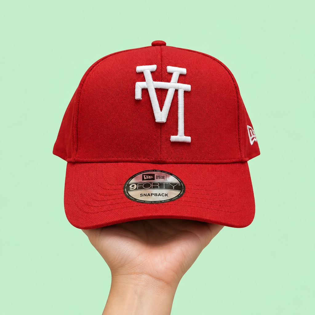 Red cap with white raised embroidery held in one hand, front view on pastel mint background