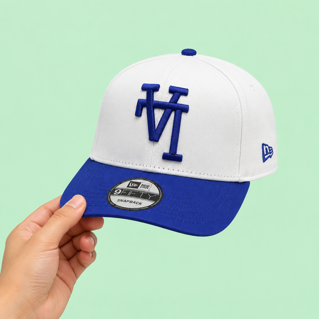 White cap with blue brim held in one hand, side-forward view on pastel mint background