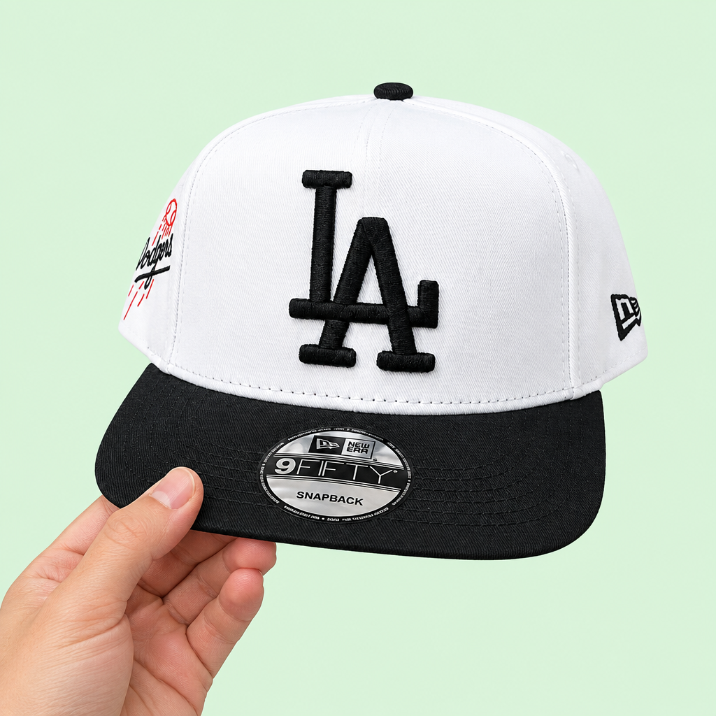 White-and-black snapback cap held in one hand, three-quarter view